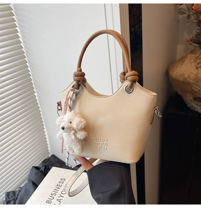 Détail du sac seau crème avec lettrage embossé et charmant pendentif chien en peluche