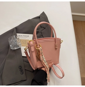 Detail of pink leather bucket bag with decorative scarf rope and gold metal pendant