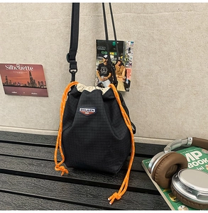 Detail of black drawstring bucket bag with bright orange ropes and tear-resistant fabric