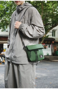 Detail of dark green nylon messenger bag with woven drawstring and brand label