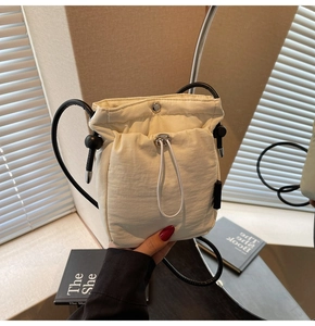 Detailed view of the ivory drawstring bucket bag with light nylon fabric texture