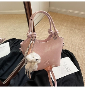 Détail du sac seau rose avec poignée nouée, breloque chiot en peluche et foulard à rayures