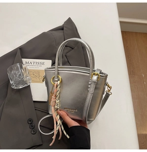 Detail of silver metallic tote bag with MINAIQI branding and elegant top handles
