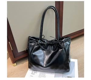 Détail du sac cabas noir à nœud avec cordon de serrage sur sol en bois