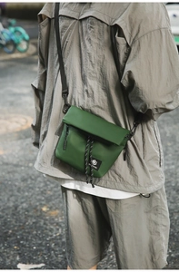 Detail of army green nylon messenger bag with toggle cord and brand logo patch