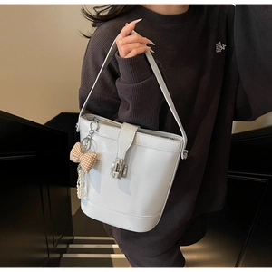 Detail of white glossy bucket bag with silver twist lock and pearl tassel charm
