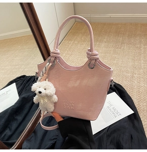 Détail du sac seau rose avec poignée nouée et breloque en peluche de chiot blanc