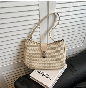Detail of the woven texture and silver metal buckle on a cream shoulder handbag