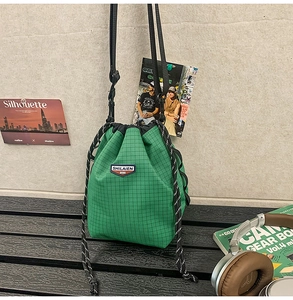 Detail of green plaid drawstring bucket bag showing urban lifestyle aesthetic and logo