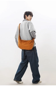 Macro detail of burnt orange nylon crescent bag showing smooth texture and wide strap