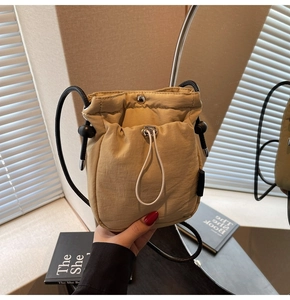 Detail of khaki drawstring crossbody bag with metallic snap closure and slim strap