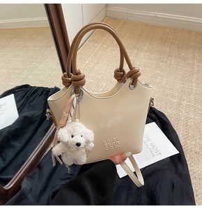 Détail du sac seau crème avec breloque chien en peluche et poignée ronde marron