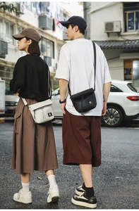 Street style shot of couple wearing compact nylon crossbody bags in black and beige