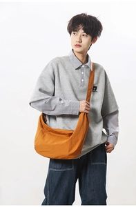 Detail of an orange nylon crescent crossbody bag styled with a grey casual sweatshirt