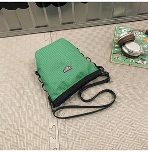 Detail of green and black patchwork bucket bag with drawstring closure and brand label