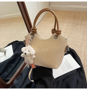 Détail du sac seau beige avec poignée nouée marron et charm de sac en peluche chien