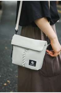 Close-up of minimalist nylon crossbody bag with flip cover and decorative drawstring detail