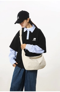 Detail view of a large cream nylon crescent bag worn across a minimalist casual outfit