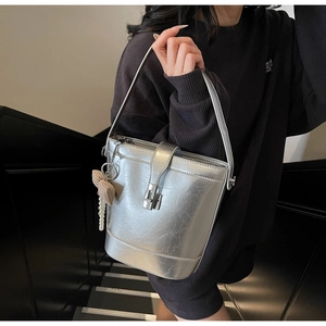 Detail of silver metallic bucket bag with pearl chain bow charm and buckle closure