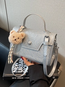 Silver textured crossbody bag with a bear charm and striped tassel accessories