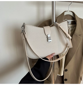 Close-up of beige woven texture shoulder bag with elegant silver metallic buckle detail