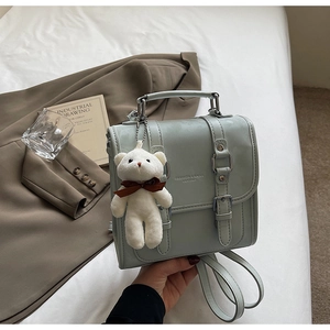 Detail of mint green vintage leather backpack with silver buckles and plush bear charm