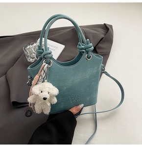 Détail du sac seau bleu canard avec poignée nouée, breloque et foulard en soie