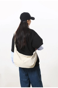 Minimalist beige nylon crescent crossbody bag shown in a stylish street style pose