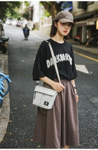 Detail of grey nylon crossbody bag featuring front zipper pocket and BLACK STUDIO woven label
