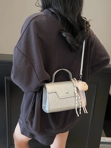 Silver square crossbody handbag with pearlized finish and plush charm accessory for women