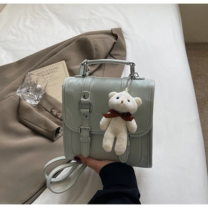 Sage green PU backpack detail with double buckle straps and teddy bear charm