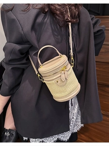 Elegante borsa a secchiello cilindrica in paglia beige con manici in pelle e tracolla