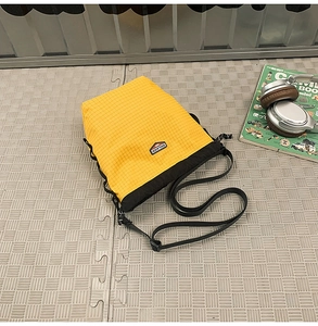 Close-up of yellow and black drawstring crossbody bag with durable grid nylon texture