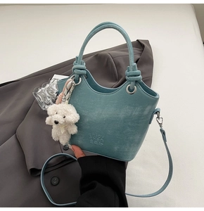 Détail du sac seau bleu clair avec texture mate et pendentif mignon en forme de chiot