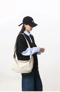 Side view of large off-white nylon dumpling bag shown on model for casual commuting