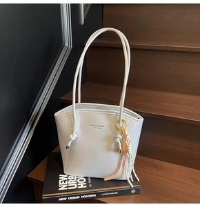 Dettaglio borsa a secchiello in pelle azzurra con logo dorato e ciondolo da tennis