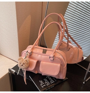 Detailansicht der rosa glänzenden Kissentasche mit Fronttaschen und Bären-Anhänger