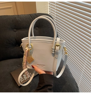 Detail of light blue bucket bag with gold hardware, tennis racket charm and silk ribbon