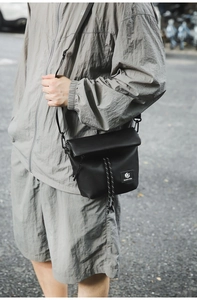 Close-up of black nylon crossbody bag with drawstring closure and brand label