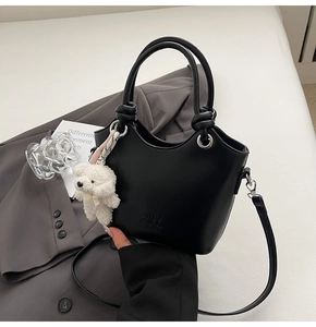Détail du sac seau noir avec lettrage embossé et adorable charm d'ours en peluche blanc
