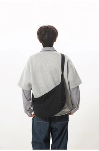 Back view of model wearing a large black crescent crossbody bag with wide shoulder strap