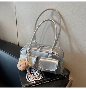 Detail der silbernen Kissentasche mit Doppeltaschen und Plüschbär-Anhänger