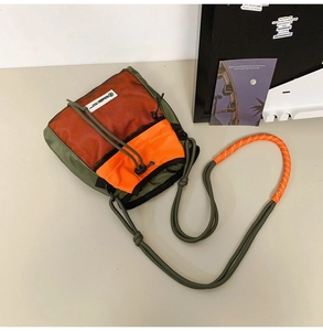 Detailansicht der olivgrünen Umhängetasche mit orangem Netzfach und Kordelzugdetail