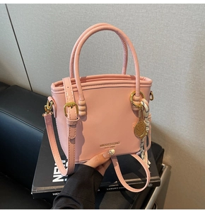 Detailed shot of pink leather bucket bag featuring a silk scarf and tennis racket charm