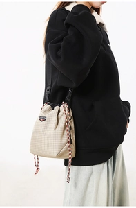 Detail of beige checkered drawstring crossbody bag with SHILAEN logo and nylon strap