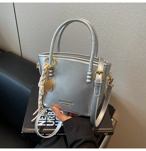 Detail of silver bucket bag with metallic finish, tennis racket charm, and silk scarf wrap