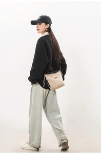Model wearing a beige drawstring crossbody bucket bag with textured grid fabric and logo