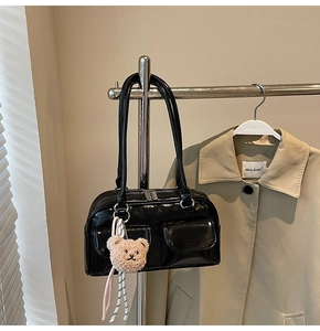 Detail der glänzenden schwarzen Pillow Bag mit Klapptaschen und Plüschbär-Anhänger