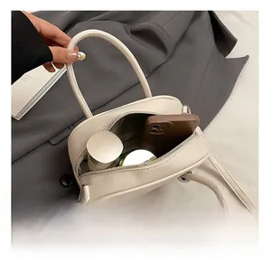 Internal view of beige satchel showing capacity for phone and cosmetics