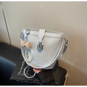 Detail of light blue bucket bag with silver clasp, pearl chain, and plaid bow charm